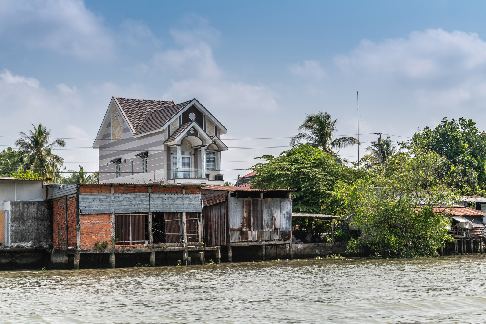 House fronted by dilapidated barns along Kinh 28 canal in Cai Be, Mekong Delta, Vietnam.