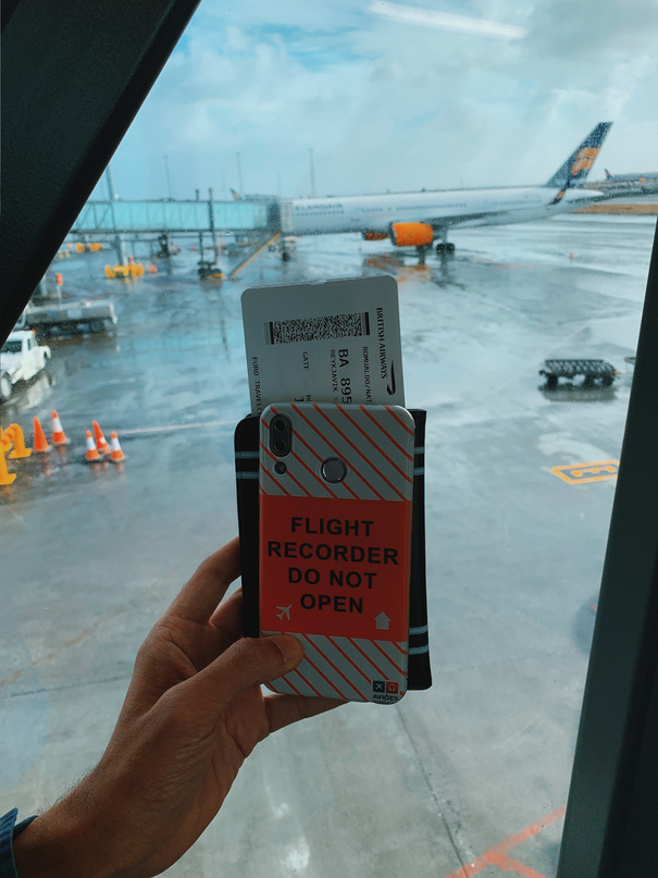 Crop traveler with smartphone and boarding pass in airport