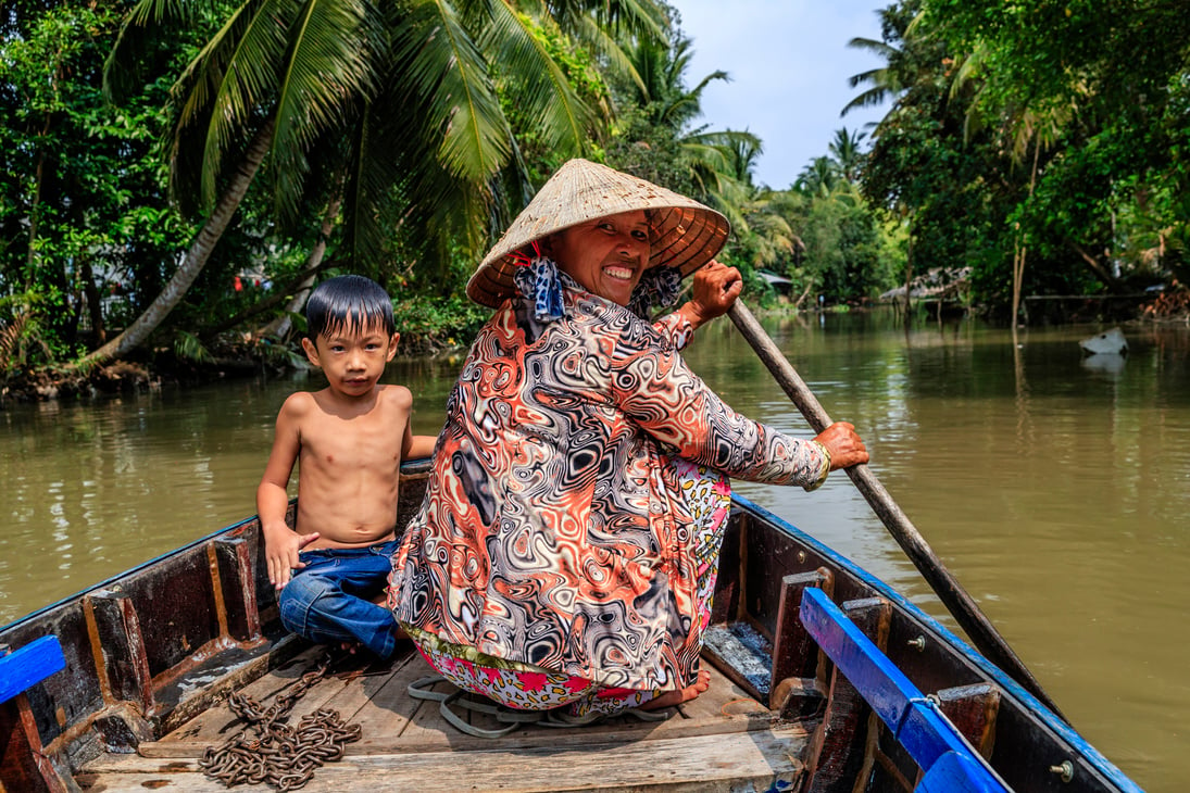 Vietnamese mother rowing a boat, Mekong River Delta, Vietnam